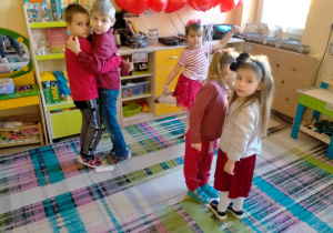 Dzieci tańczą w parach na poskładanych papierowych sercach.